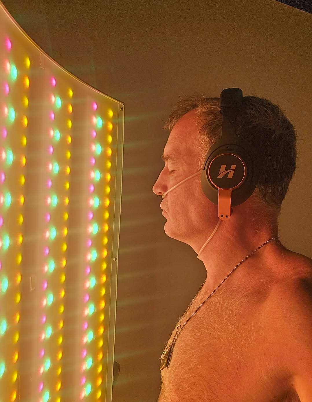 A person wearing headphones beside a coloured light panel at the Smart Fit Recharge Station