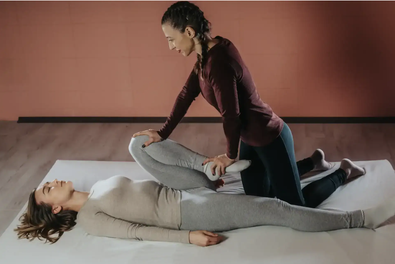 A practitioner guiding an assisted stretch during a bodywork session